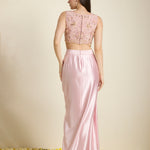 Woman wearing a pink lace top and satin skirt set on a neutral background