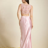 Woman wearing a pink lace top and satin skirt set on a neutral background
