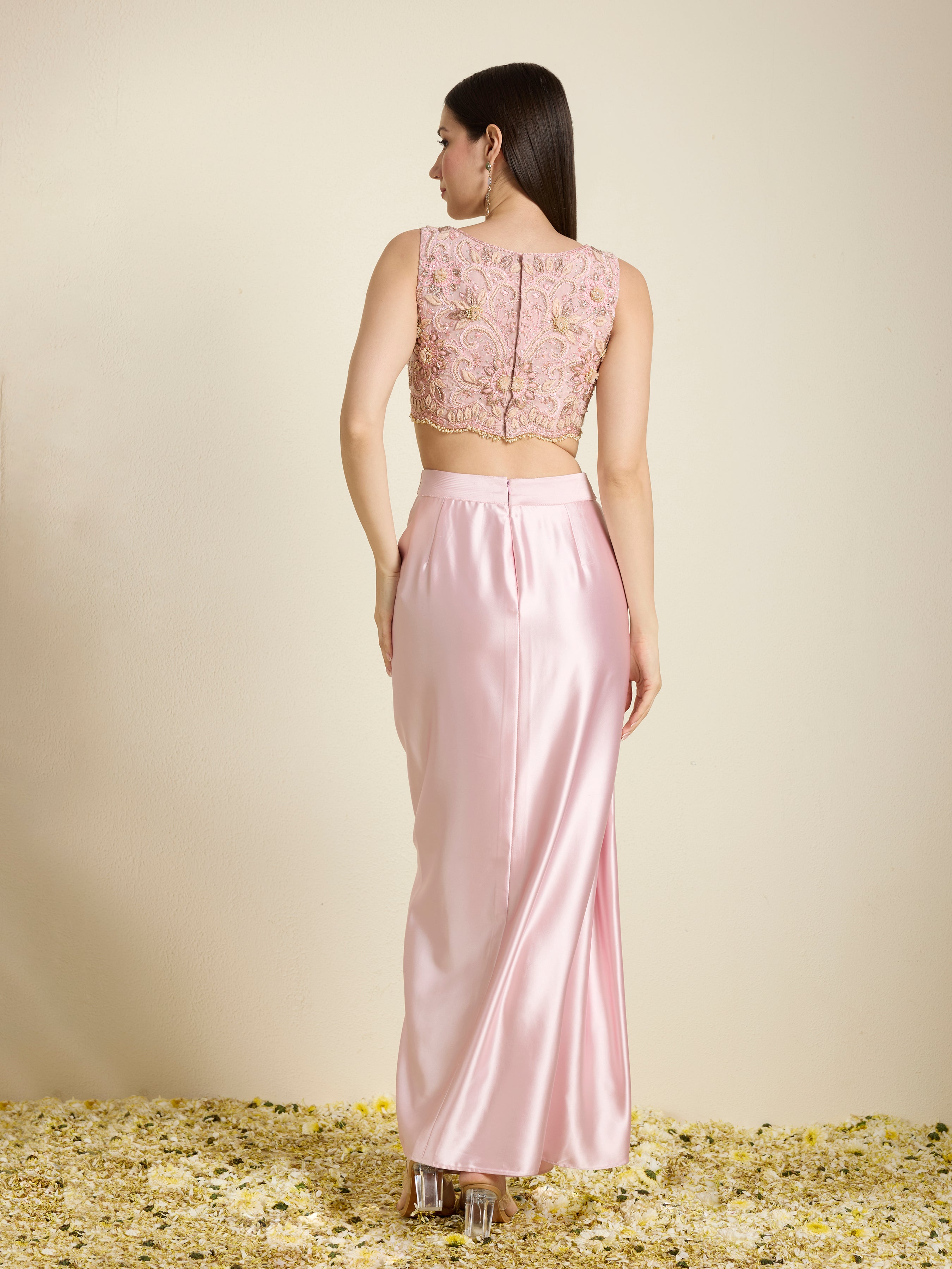 Woman wearing a pink lace top and satin skirt set on a neutral background