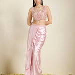 Woman wearing a pink traditional outfit with a top and saree on a beige background