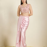 Woman wearing a pink traditional outfit with a top and saree on a beige background
