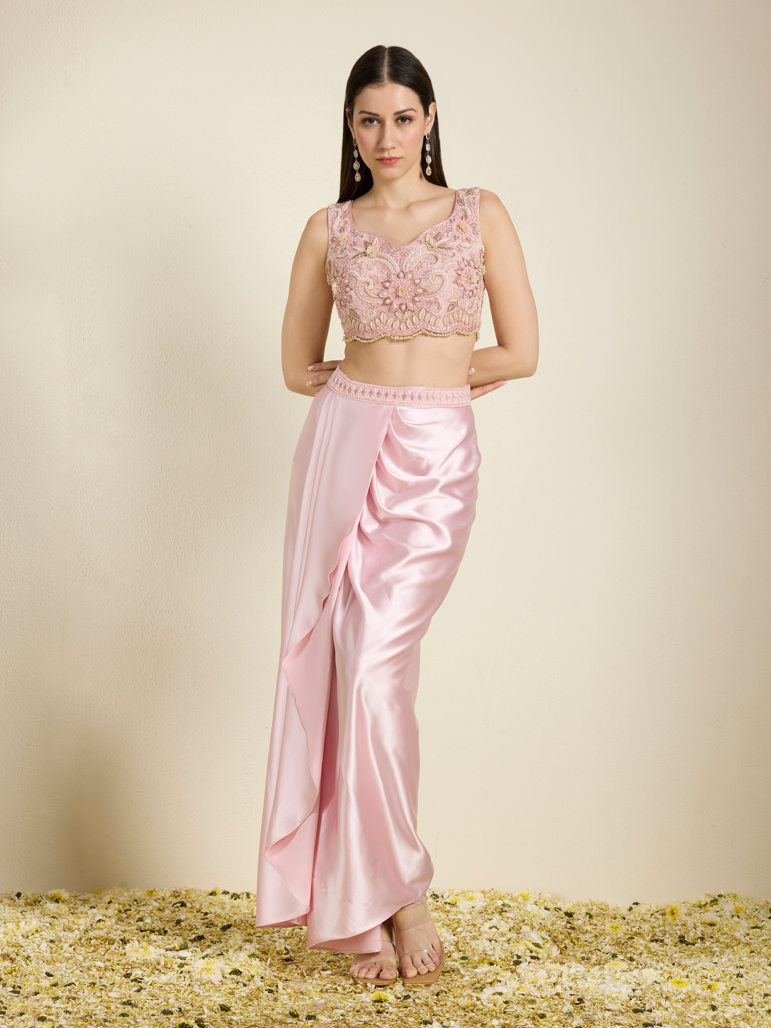 Woman wearing a pink traditional outfit with a top and saree on a beige background