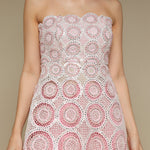Woman wearing a pink and white lace top against a beige background