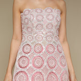 Woman wearing a pink and white lace top against a beige background
