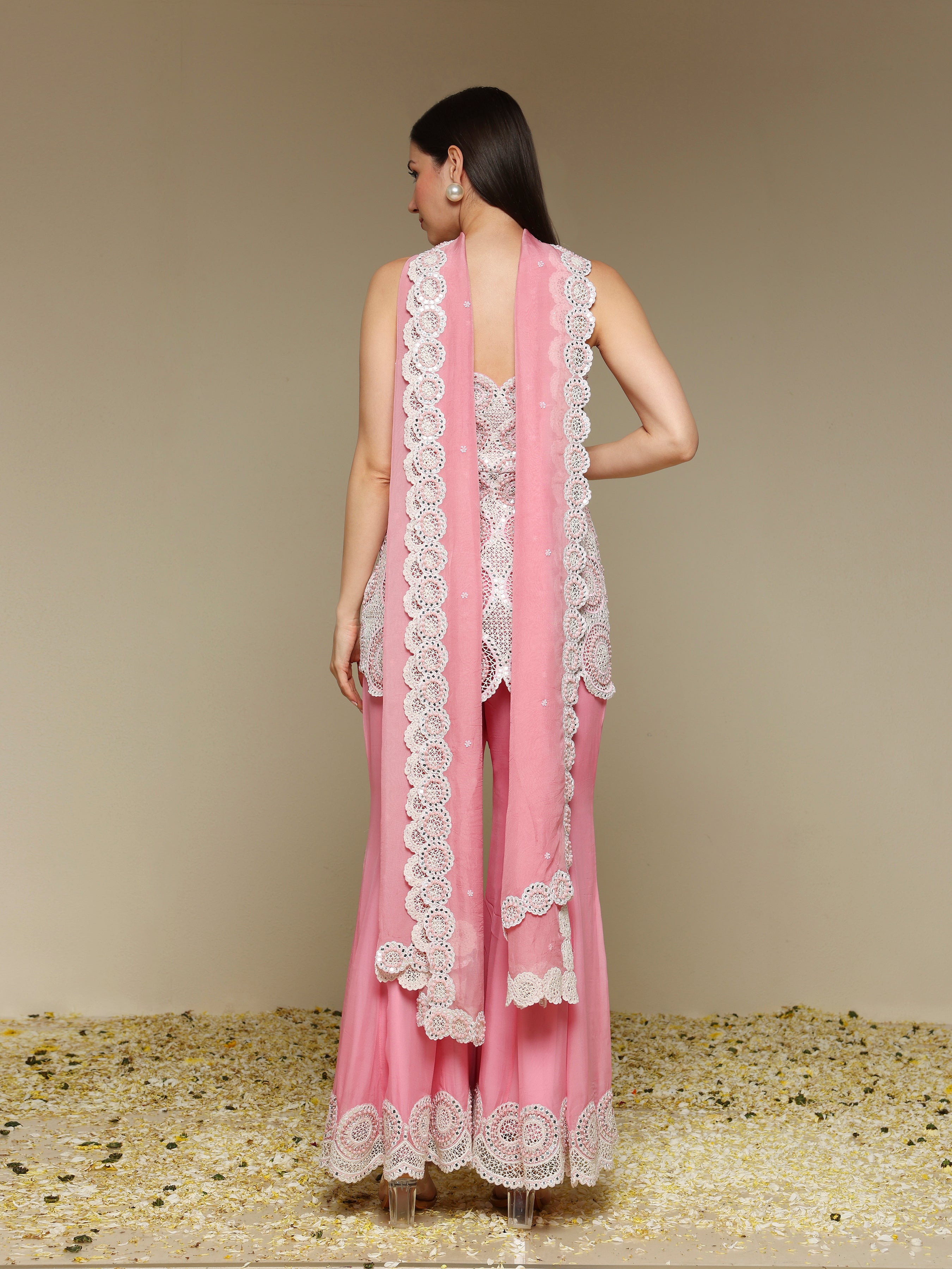 Woman wearing a pink outfit with white lace details on a beige background
