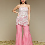 Woman wearing a strapless top and pink pants with lace details against a beige background