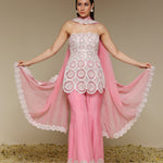Woman wearing a pink and white outfit with a sheer dupatta against a beige background
