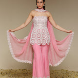 Woman wearing a pink and white outfit with a sheer dupatta against a beige background