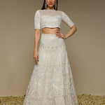 Woman wearing an ivory lehenga outfit showcasing pearl and threadwork embellishments